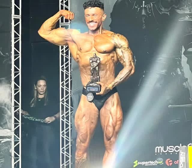 Rafael Calil no palco de uma competição de fisiculturismo com o troféu